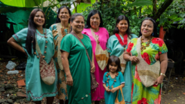 Seis mujeres y una niña posan con trajes y accesorios típicos indígenas.