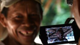 Fotografía de un hombre indígena posando ante una cámara de video.