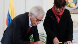 Fotografía de Medófilo Medina, nuevo director del ICC, firmando su acta de posesión del cargo. Lo acompaña Patricia Ariza, ministra de Cultura de Colombia.