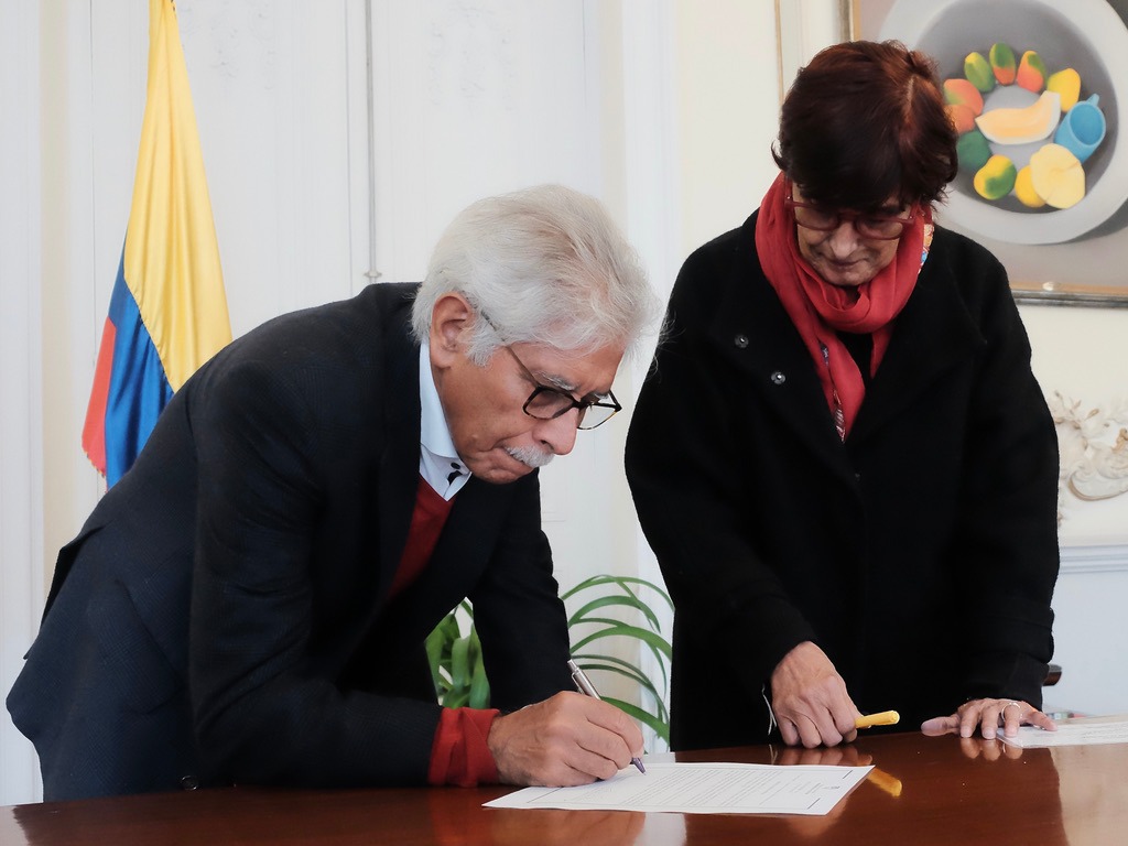 Fotografía de Medófilo Medina, nuevo director del ICC, firmando su acta de posesión del cargo. Lo acompaña Patricia Ariza, ministra de Cultura de Colombia.