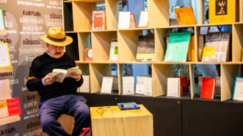 Fotografía de un hombre leyendo un libro en el estand del ICC de la FILBo 2023.